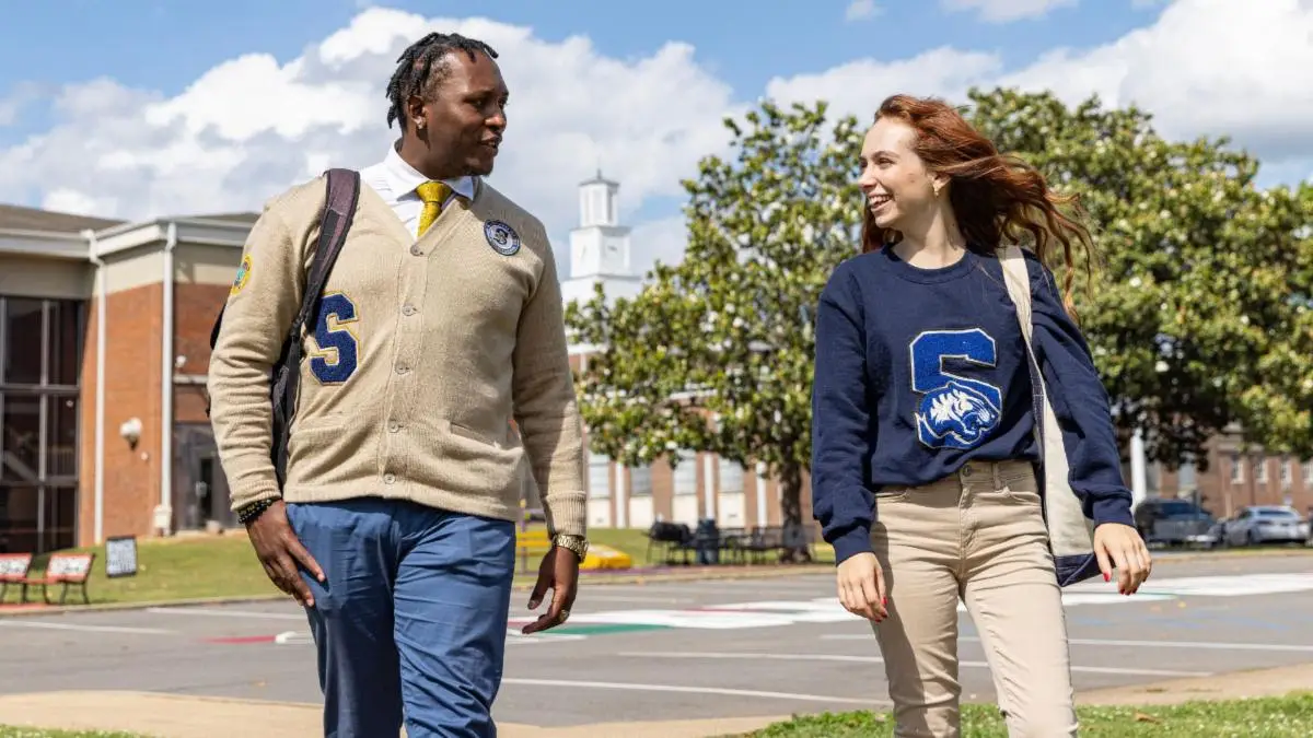 Two Stillman students walking together on campus, wearing a lettered Stillman cardigan and a navy Stillman Tigers sweatshirt
